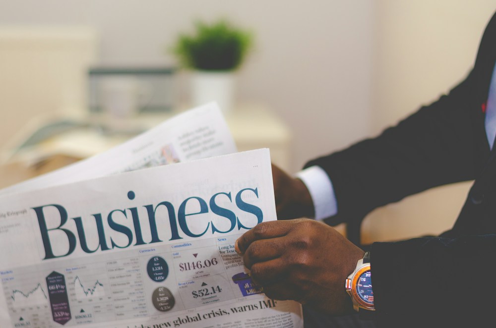 A reader holding a business newspaper