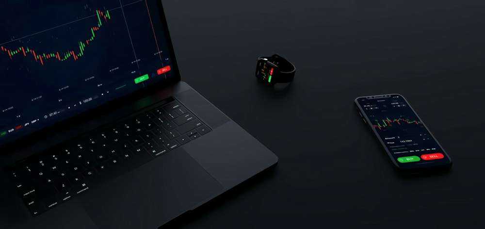 A laptop and phone showing illustrative financial charts